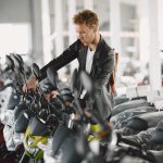 Homem observa motocicletas em exposição no interior de uma concessionária.