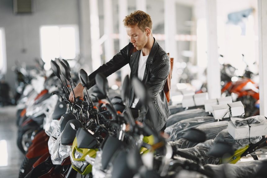Homem observa motocicletas em exposição no interior de uma concessionária.