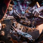 Profissional monta peças de um motor de motocicleta em uma oficina.