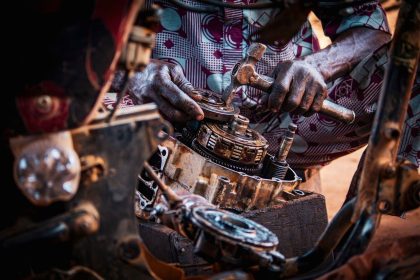 Profissional monta peças de um motor de motocicleta em uma oficina.