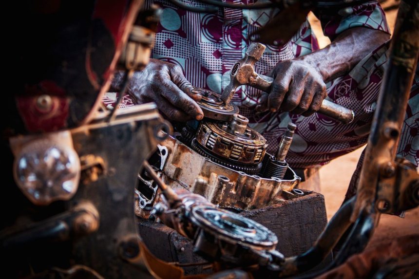 Profissional monta peças de um motor de motocicleta em uma oficina.