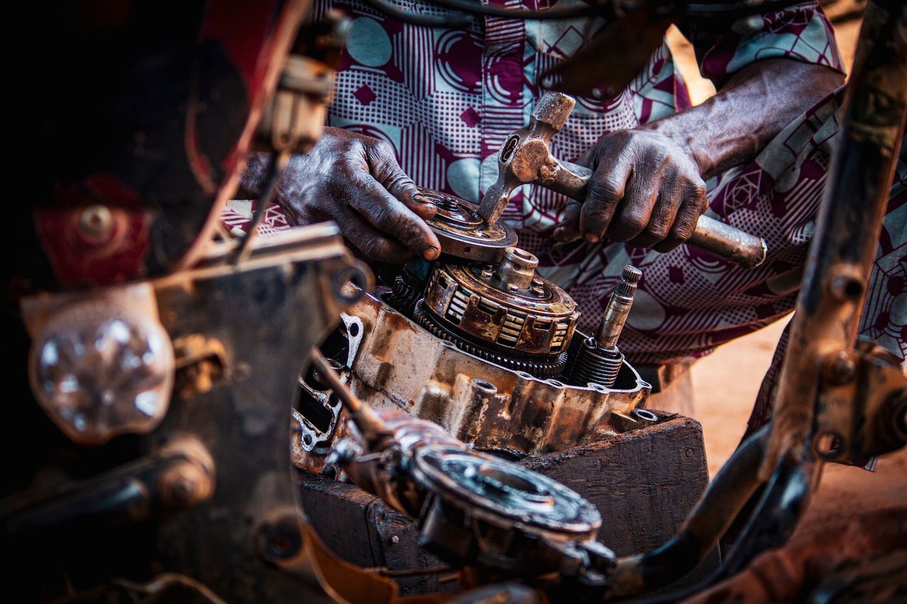 Profissional monta peças de um motor de motocicleta em uma oficina.