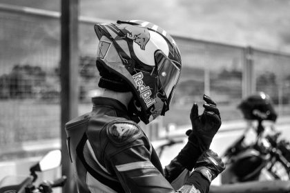 Motociclista com equipamento de proteção ajusta o capacete ao ar livre.