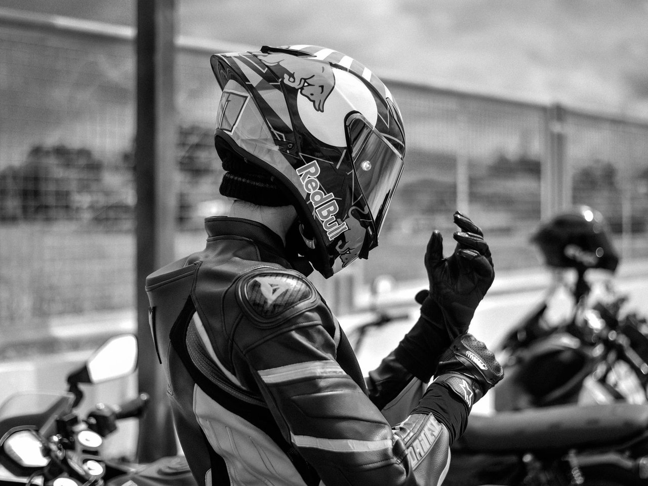 Motociclista com equipamento de proteção ajusta o capacete ao ar livre.