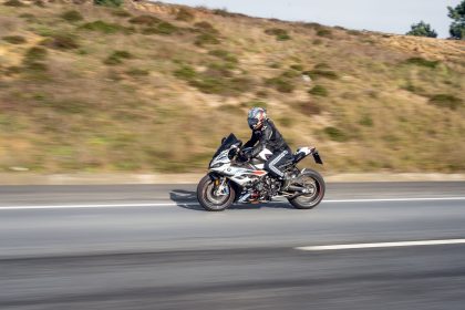Motociclista usando capacete conduz uma motocicleta esportiva em uma rodovia de pista aberta.
